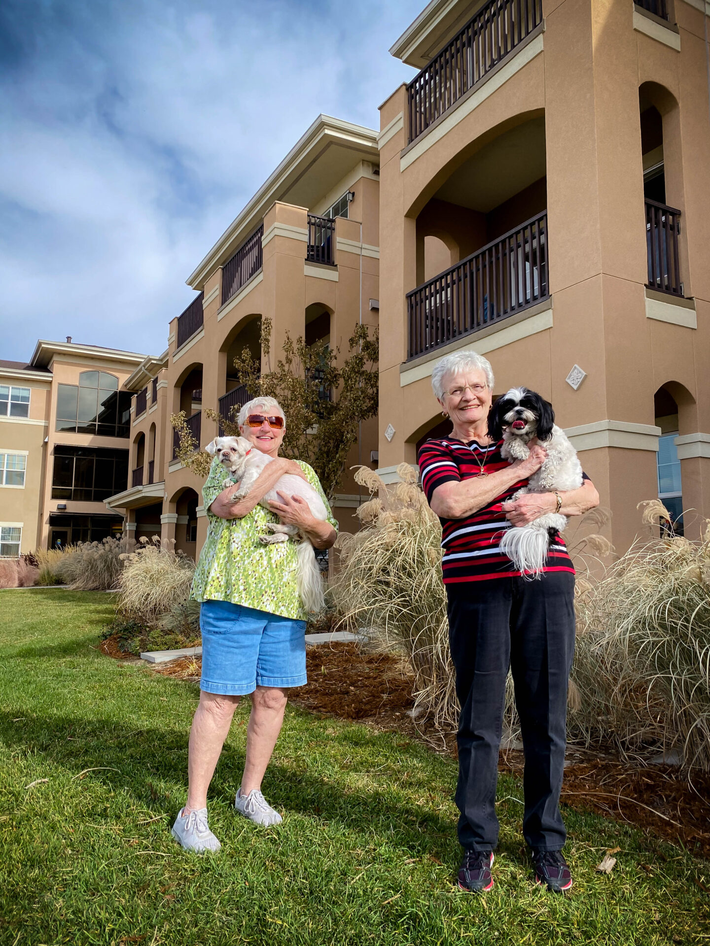 Two women holding dogs in front of a building.